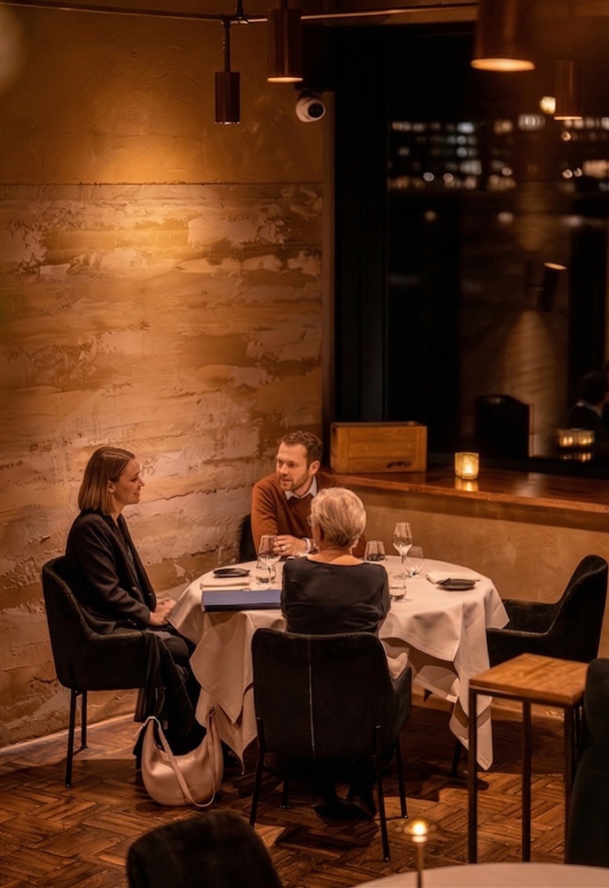 Gasten aan een ronde, gedekte tafel in restaurant MOS, bij warm licht